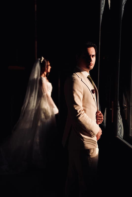 Portret de mire lângă fereastră, cu mireasa neclară în fundal