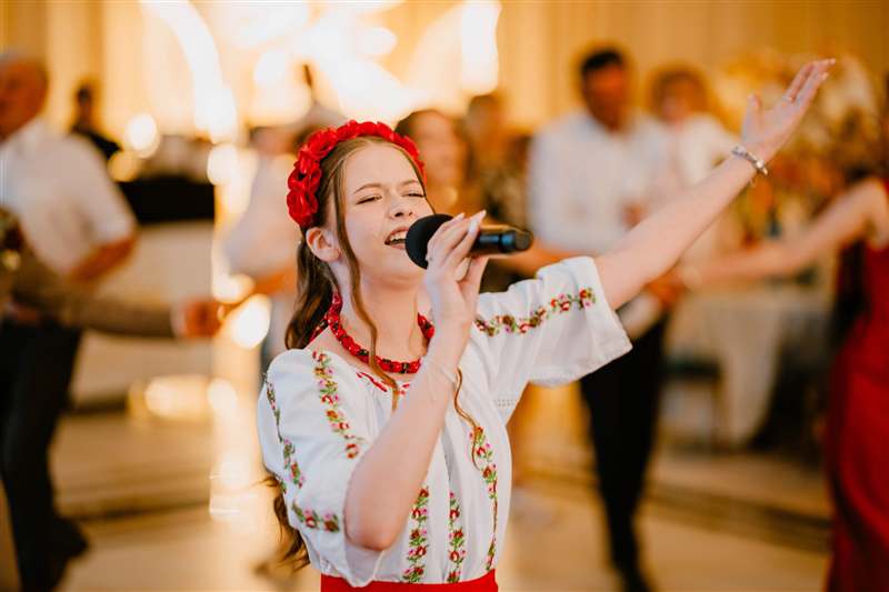 Solistă în costum popular cântând la petrecere